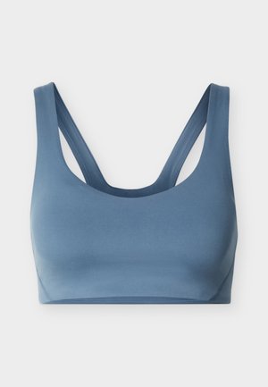 Kék, széles vállpántokkal és mély kivágással rendelkező sportmelltartó, amely atlétikai támogatást és kényelmet biztosít.