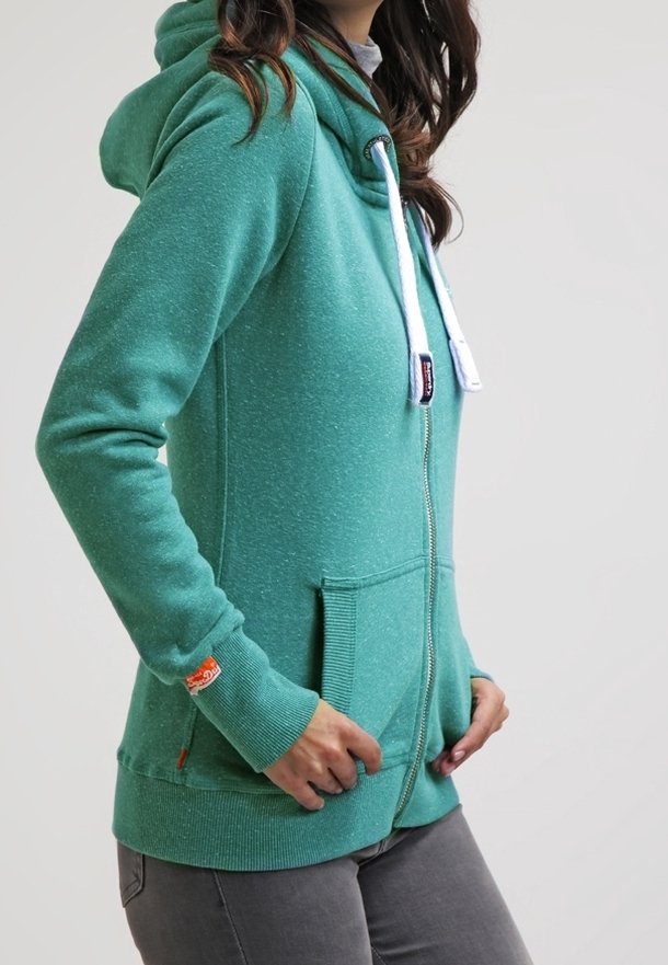 Sudadera con cremallera verde de tela texturizada, con capucha ajustable, bolsillos tipo canguro y puños acanalados. Acento de logo naranja en la manga.