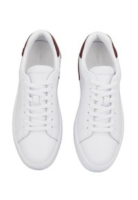 Un paio di sneakers bianche a bassa altezza con lacci bianchi e accenti maroon sul tallone, viste dall'alto su uno sfondo bianco.