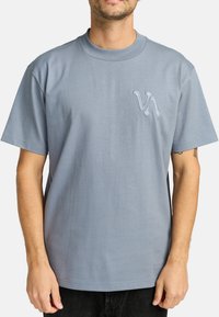 Lichtblauwe katoenen T-shirt met een ronde hals, korte mouwen en een klein geborduurd logo op de linkerborst. Zachte textuur, relaxte pasvorm.