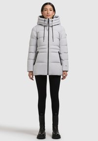 Lysegrå dunjakke med høj krave, lodrette syninger og lynlåslommer, med sorte detaljer og snore til justering.