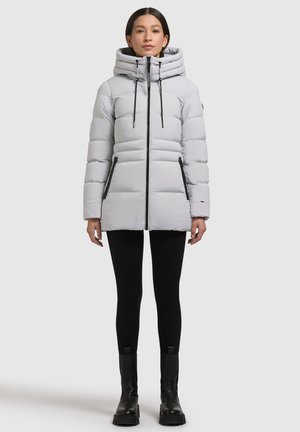 Ljusgrå vadderad jacka med hög krage, vertikal sömnad och fickor med dragkedja, med svarta detaljer och dragsnören för justering.