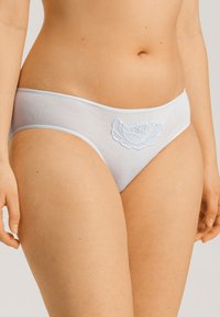 Vaaleansiniset puuvillapikkarit, joissa on pitsikukkakuvio etuosassa. Suunnittelu on saumaton ja siinä on pehmeä, sileä rakenne.