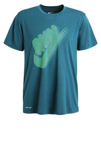 Teal bomullströja med rundad hals, med en flerfärgad Nike-logotyp som är tryckt diagonalt. Inkluderar Dri-FIT etikett vid fållen.