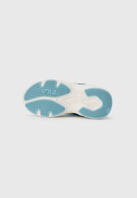 Semelle d'une sneaker FILA blanche et bleue avec des motifs de grip texturés et le logo visible sur la zone du talon.