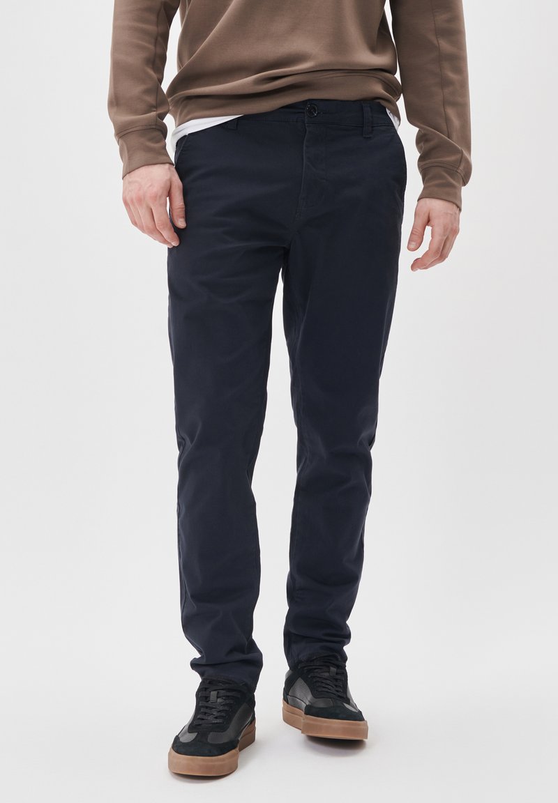 Pantaloni chino subțiri, de culoare bleu marin, confecționați dintr-un material din bumbac cu o finisare netedă, dotati cu o închidere prin buton și fermoar, precum și cu lasete pentru curea.
