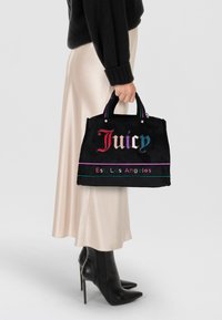 Borsa a mano in tessuto nero con logo "Juicy" colorato, hardware argentato e manici a righe in contrasto. Forma rettangolare, design compatto, texture liscia.