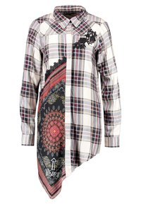 Camisa de manga larga a cuadros en blanco, rojo y azul marino, con acentos florales negros y un panel negro con un patrón que presenta un motivo rojo y texto.