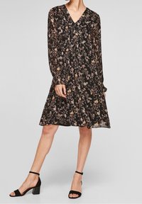 Abito floreale nero con maniche lunghe, scollatura a V e silhouette fluida. Presenta un delicato motivo di fiori in vari colori.