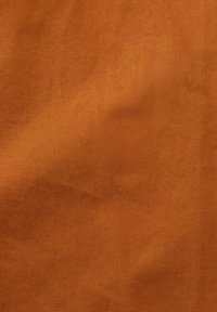 Tejido de algodón en un cálido color naranja quemado, con una textura suave y uniforme, sin patrones o embellimientos visibles.