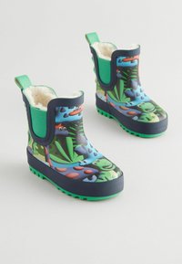 Bottes en caoutchouc bleues avec un motif de dinosaure, des accents verts et une doublure douce. Dotées d'une semelle texturée pour une meilleure adhérence et de languettes pour un enfilage facile.