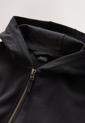 Schwarzer Kapuzenpullover mit durchgehendem Reißverschluss in Gold und Kordelzug. Verfügt über eine weiche Textur und ein Etikett innen mit der Markenbezeichnung „NEXT“.