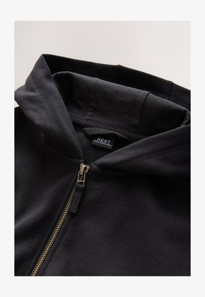 Zwarte hoodie met ritssluiting in goudkleur en trekkoord. Heeft een zachte textuur en een label binnenin met het merk "NEXT."
