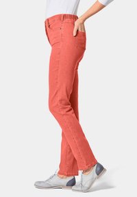 Rode stretchdenim broek met een slim fit, voorzien van een middelhoge elastische tailleband en zijzakken, gecombineerd met grijze en blauwe oxford schoenen.