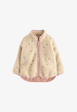 Giacca in pile crema con bordo rosa, piccolo ricamo floreale, zip frontale e orlo stondato asimmetrico.
