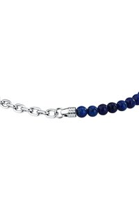 Bracciale con perline in lapislazzuli e collegamenti a catena e chiusura in tono argento. Presenta perle rotonde, di un profondo blu con macchie più chiare.