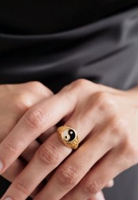 Goldring mit strukturiertem Design, versehen mit einem Yin-Yang-Symbol aus schwarzem und weißem Emaille, geschmückt mit kleinen klaren Edelsteinen.