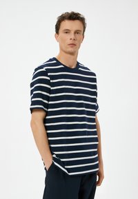 Marineblå og hvid stribet bomulds t-shirt med rund halsudskæring, korte ærmer og sidelæg. Blød tekstur, afslappet pasform.