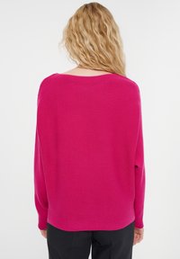 Helles pinkes Sweatshirt mit lockerer Passform, geripptem Texture und weitem Ausschnitt, schmalen Ärmeln und leicht abgerundhem Saum.