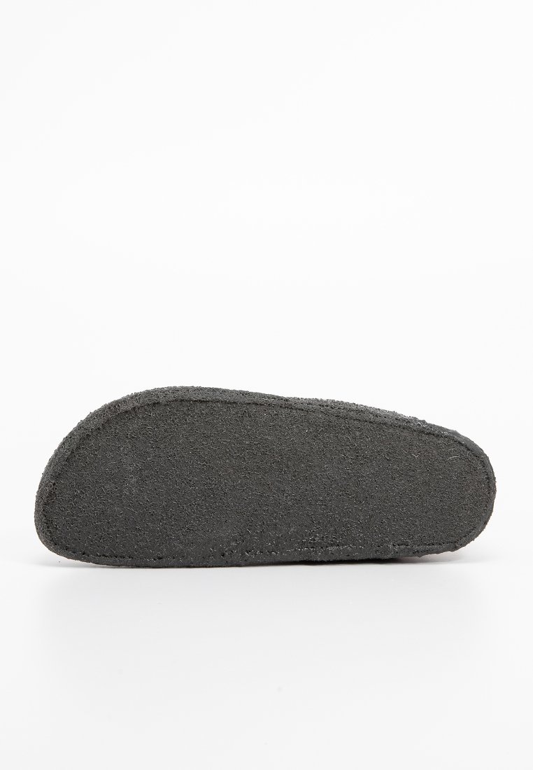 Schwarze Gummisohle mit strukturierter Oberfläche, abgerundeten Kanten und flachem Boden. Entwickelt für Komfort und Unterstützung.