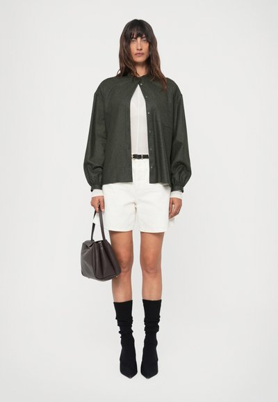 Dark green button-up shirt, white shorts, black knee-high socks, pointed black heels, and a small dark brown handbag.