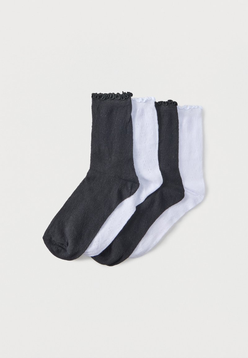 Quatre chaussettes chevilles aux couleurs alternées noir et blanc, chacune avec un bord supérieur froncé, posées à plat sur un fond uni.