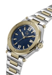 Vīriešu pulkstenis ar tumši zilu teksturētu ciparnīcu, zelta tonī nerūsējošā tērauda rāmī, kā arī sudraba un zelta metāla ķēdi. Iespējas ietver romiešu skaitļus un datuma indikatoru.