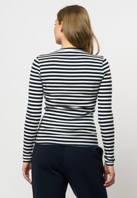 Langermet topp i marineblå og hvite horisontale striper, laget av ribbestrikket stoff. Har rund hals og tettsittende design.