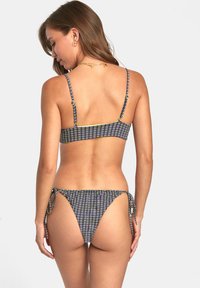 Conjunto de bikini con patrón a rayas en azul marino, blanco y amarillo. La parte superior tiene tirantes finos; la parte inferior cuenta con lazos ajustables a los lados.