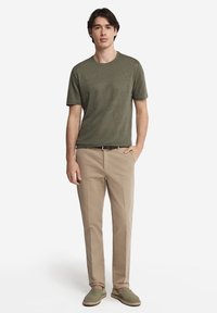 Khakifärgade byxor med rak skärning, kombinerade med en texturerad olivgrön crew neck t-shirt och ljusgröna pumps. Enkel design, inga mönster.