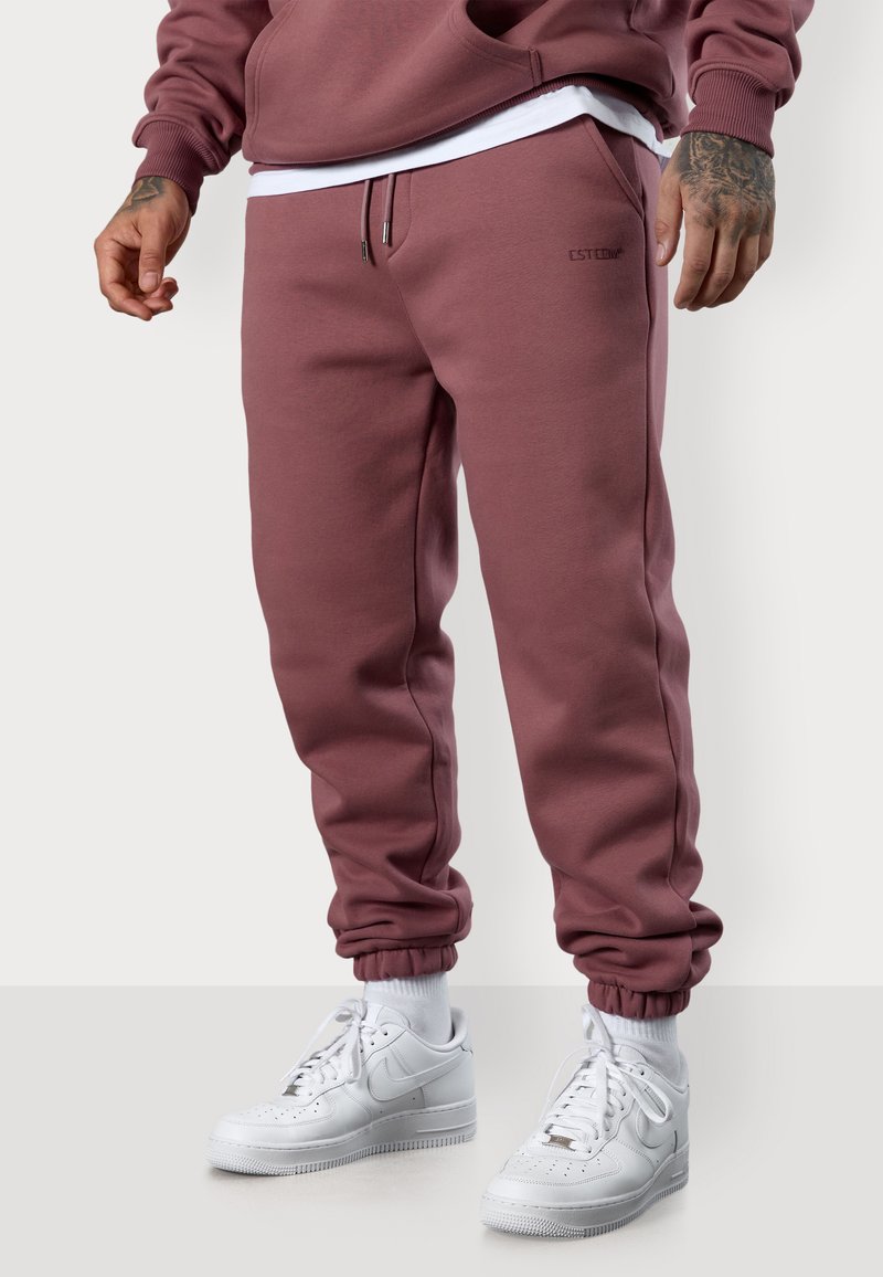 Bordeauxfarbene Jogginghose aus weichem Material, mit einem elastischen Bund und Bündchen, einem dezenten Logo auf dem Oberschenkel und Seitentaschen.
