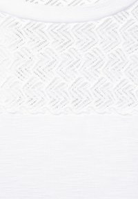 Bílý látkový top se tkaným krajkovým výstřihem se vzorem cikcak a hladkou, jemně texturovanou spodní částí.