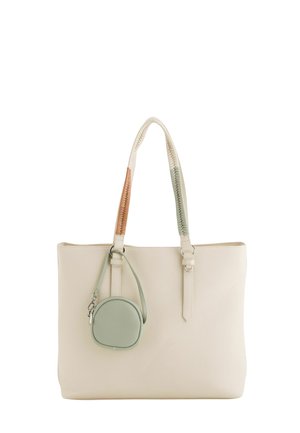 Bolsa tote color crema con asas cosidas bicolor y pequeño monedero redondo verde adjunto con cremallera y correa para la muñeca.