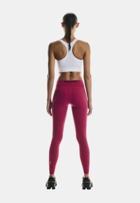 Kitsad, kõrge vöökohaga retuusid erksas roosas, koos valge sportliku lühikese ülikonnaga, millel on racerback disain ja sile tekstuur.