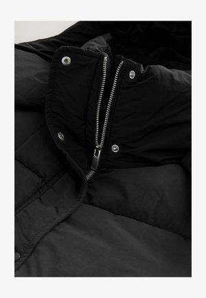 Sort puffer-jakke med høj krave, metallisk lynlås og trykknapper. Stoffet ser glat ud med quiltede sektioner.