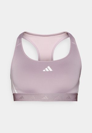 Lilac sporta krūšturis ar racerback dizainu, gludu tekstūru un kontrastējošu baltu logotipu. Ievieš subtile joslu ar atkārtotu logotipa rakstu.