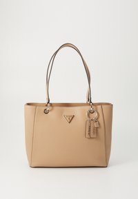 Beige leren shopper met dubbele handvatten, driehoekig Guess-logo en sleutelhangerlabels met de tekst "Guess" en "1981" en een kleine hangslotbedel.