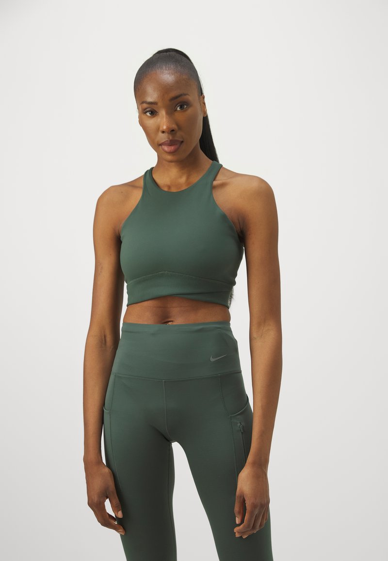 Mörkgrön sport-bh med hög halsringning, kombinerad med matchande högmidjade leggings med sidoficka och diskret logotyp.
