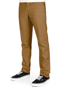 Chinos marroni con una texture liscia, design a gamba dritta e fronte piatto, abbinati a sneakers nere con lacci bianchi e suola in gomma.