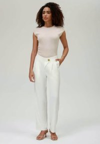 Beige fitted ribbed top paired with white wide-leg trousers featuring a gold button detail. Smooth texture with a tailored design.