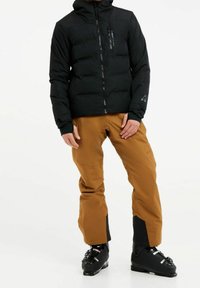 Veste rembourrée noire avec capuche, fermeture éclair sur le devant et poches latérales. Pantalons de ski bruns avec bas renforcés. Bottes de ski noires avec sangles de fixation.