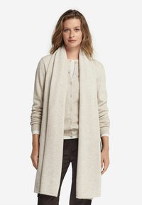 Cardigan beige clair avec une écharpe assortie, doté d'une fermeture à boutons et de poignets côtelés. Texture douce et écharpe longue et drapée.