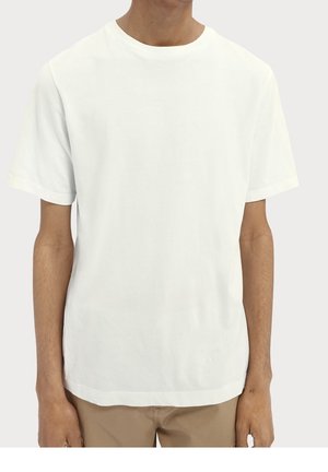 Mand iført en ensfarvet hvid kortærmet T-shirt og lysebrune bukser, vist fra nakke til hofter mod en neutral baggrund.