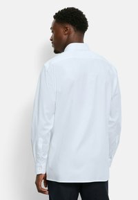 Weißes Hemd mit geradem Saum, langen Ärmeln und geknöpften Manschetten; glatter Stoff ohne Muster; klassisches Kragen Design.