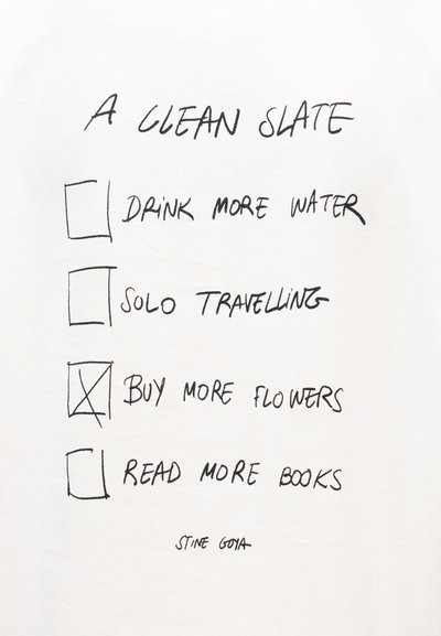 Λευκό μπλουζάκι με χειρόγραφη μαύρη γραφή. Περιλαμβάνει τέσσερις στόχους με κουτάκια επιλογής, ένα από τα οποία είναι σημειωμένο. Η λέξη "STINE GOYA" είναι τυπωμένη στο κάτω μέρος.