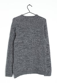 Grauer Pullover mit strukturiertem Strickdesign, rundem Ausschnitt und langen Ärmeln. Der Saum hat einen leicht gebogenen Schnitt. Hängt an einem schwarzen Haken.