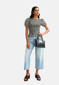 Black and white checkered puff-sleeve top, light blue wide-leg jeans, black handbag, and black platform sandals. Smooth fabric and structured design.