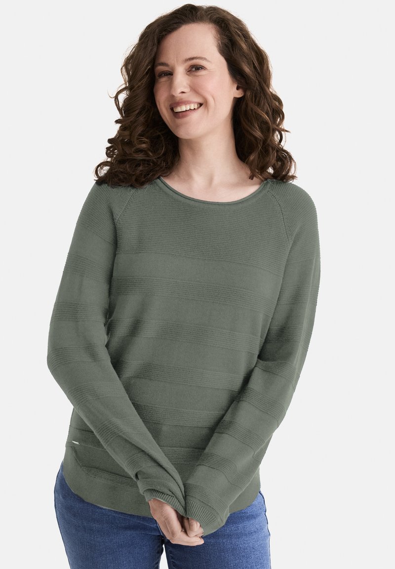 Grüner gestrickter Pullover mit horizontalen Streifen, einem runden Ausschnitt und langen Ärmeln in entspannter Passform. Kombiniert mit blauen Jeans.