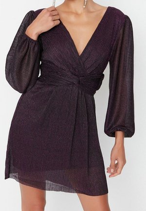 Paarse mini-jurk met een diepe V-hals, lange doorschijnende mouwen en een geplooide taille. De stof heeft een subtiele glans en een lichte textuur.