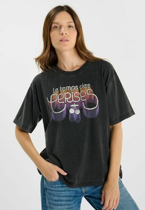 Zwarte oversized t-shirt van katoen, met een kleurrijk grafisch ontwerp met kersen. Ronde hals en korte mouwen.